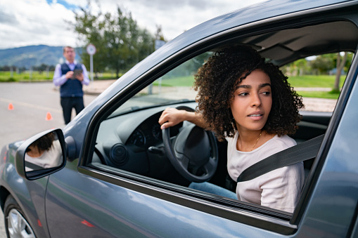 African American woman parallel parking on her driving test - learning to drive concepts