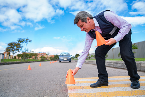 Driving instructor putting traffic cones on the ground for a driving test