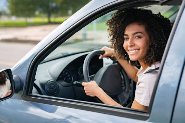 portrait of a happy woman driving her car - car test drive car rental women imagens e fotografias de stock