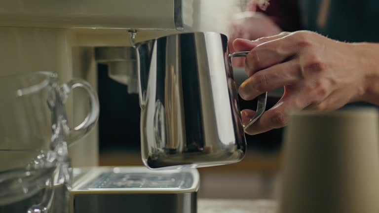 Machine, expert barista holding a milk pitcher in a small restaurant. Smooth camera movement