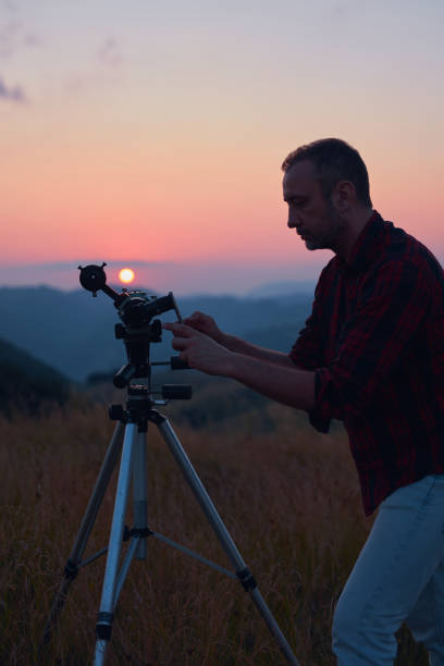 istock Astronomer looking at the sun with a telescope and using a cellphone. 1582807682