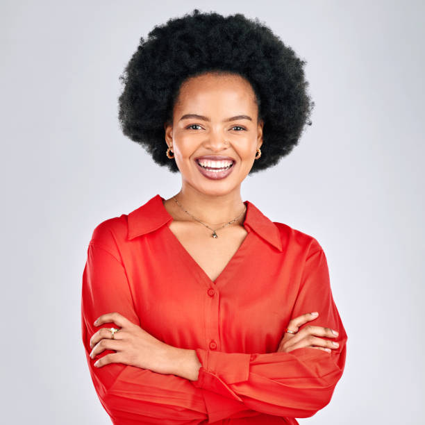 Happy black woman, portrait and afro with arms crossed in fashion against a white studio background. African female person smile in confidence for career ambition, pride or proud with clothing style Happy black woman, portrait and afro with arms crossed in fashion against a white studio background. African female person smile in confidence for career ambition, pride or proud with clothing style isolated businesswoman isolated on white beauty stock pictures, royalty-free photos & images