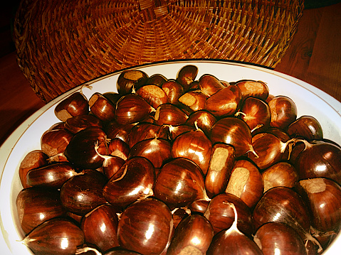 A basket full of chestnuts with its lid behind