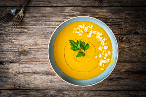 Cream carrot soup with almonds on wooden table