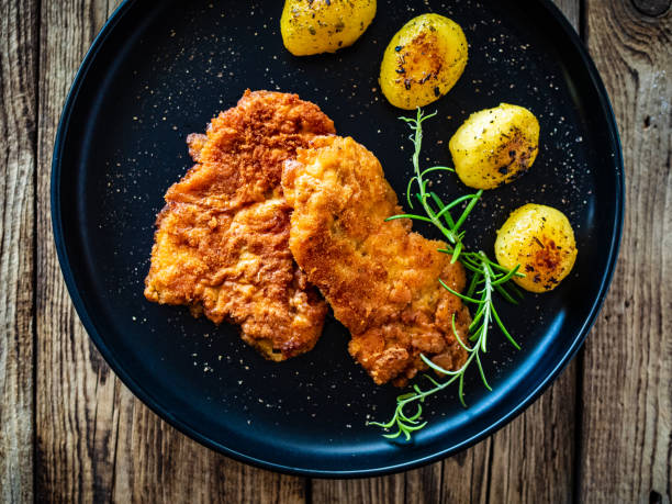 istock Breaded fried pork chop with fried potatoes and fresh vegetables on wooden table 1582901367