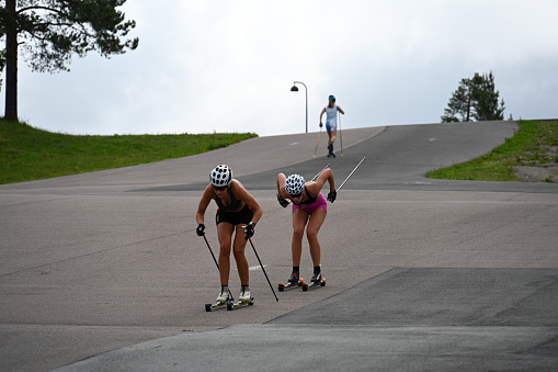 Oslo, Norway, July 5, 2023 - Athletes train with ski rollers on asphalt track Cross-country skiing - biathletes training at Holmenkollen in Oslo.