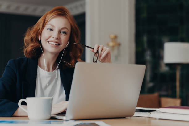 istock Ginger freelancer, remote work, laptop, ideas, video call, earphones, hot drink, happy pose. 1582937406