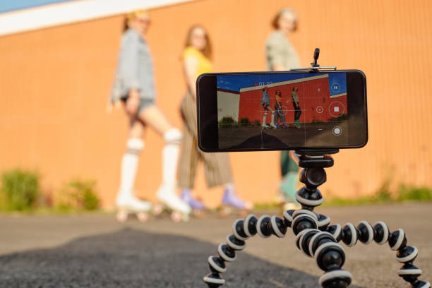 istock Focus on tripod with smartphone during video shooting of three roller skaters 1582940152