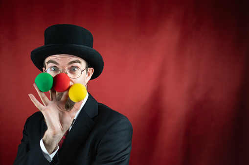 Vintage Caucasian Magician with top hat, glasses and mustache with colored balls with red background