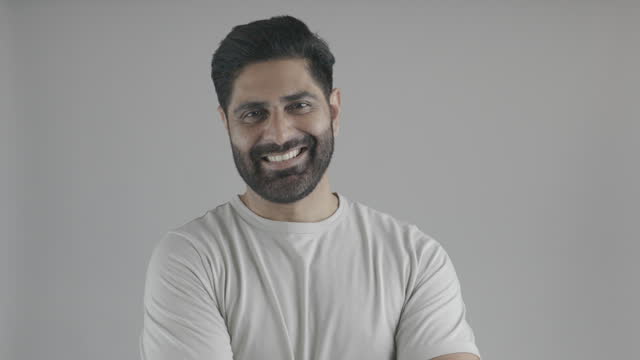 Portrait of man removing eyeglasses over white background