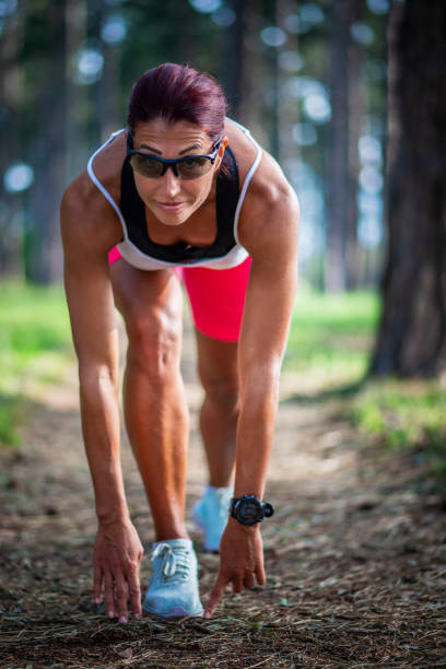Woman jogger in ready position, training at park.
