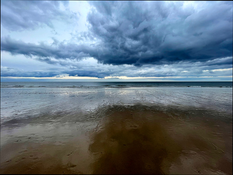 Dramatic clouds reflected on the beach