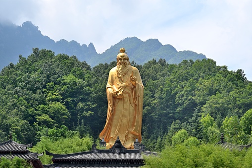 buddha statue on a rock lakeside, natural spa background with asian spirit, tranquility in green nature, web banner concept with copy space