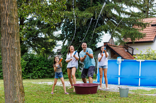 Family with two daughters enjoying water fight with water guns.