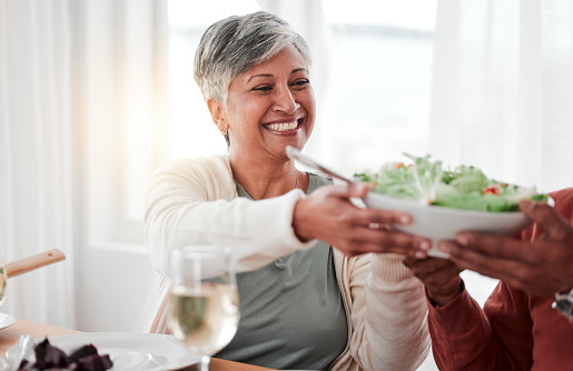 Family dinner, senior woman and salad of a happy female with heathy food in a home. Celebration, together and people with unity from eating at table with happiness and a smile in a house giving meal