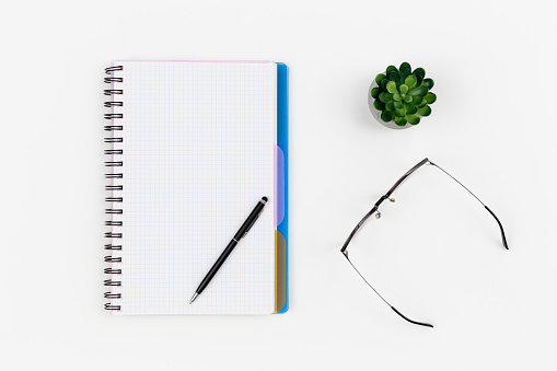 Notepad, glasses and pen on a white background isolated, top view, copy space.