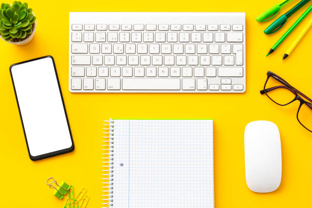 istock Yellow colored office desk: Computer keyboard and mouse, mobile phone and office accesories 1583047092