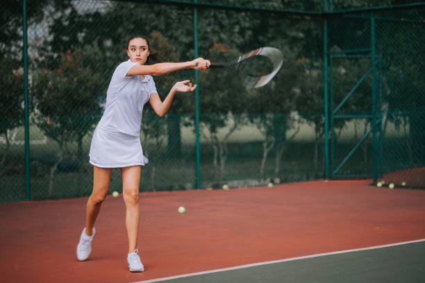 una adolescente jugadora de tenis practicando jugando en la cancha de tenis - tennis serving female playing fotografías e imágenes de stock
