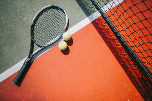 palla da tennis e racchetta su campo duro sotto la luce del sole - toughness surface level court tennis foto e immagini stock