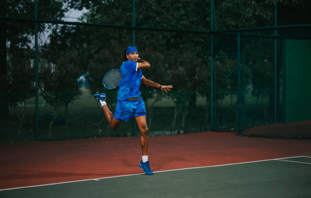 tennista asiatico maschile che pratica giocando nel campo da tennis - tennis asian ethnicity male forehand foto e immagini stock