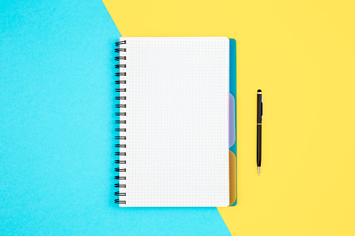 Open spiral notepad on blue yellow background, flat lay, copy space.