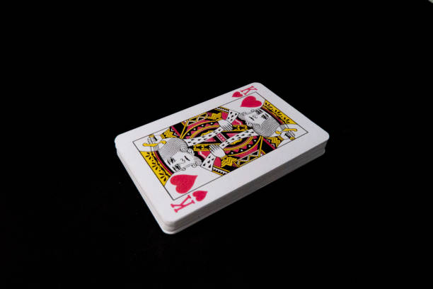 Deck of playing cards standing on black background and king is on top of the deck.