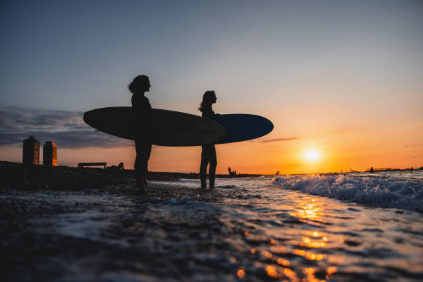 istock Two Female Surfers In Wetsuits Walking Into The Ocean With Their Surfboards During A Beautiful Sunset In Barcelona 1583061384