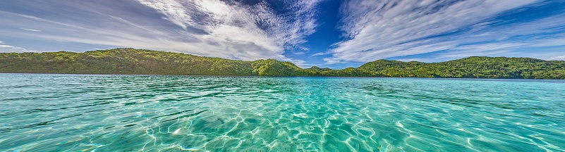 Panoramic view over turquoise blue water to a tropical island in Palau during daytime