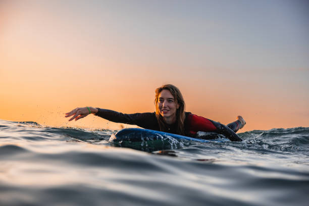 istock Attractive Surfer Girl Paddling On A Surfboard During A Sunset 1583061451