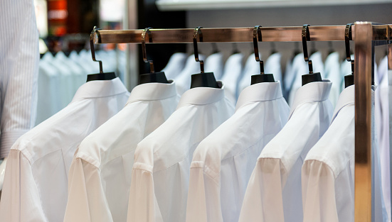 Row of cloth hangers with white shirts