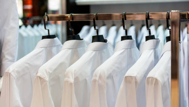 Row of cloth hangers with white shirts stock photo