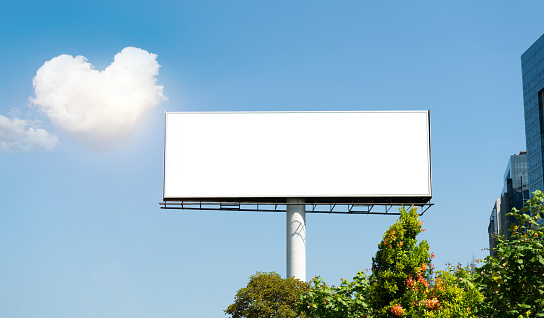 Blank outdoor billboard against blue sky with heart shape cloud
