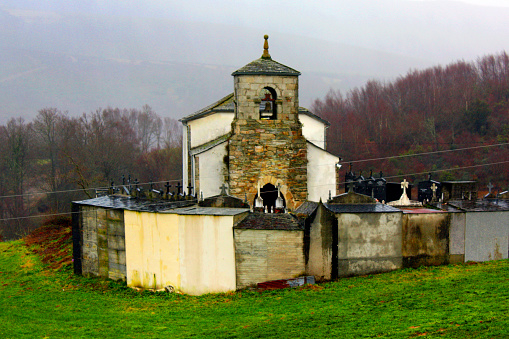Ancient Santa Mariña de Librán rural church with cemetery around, winter landscape, Baleira, Lugo province, Galicia, Spain.