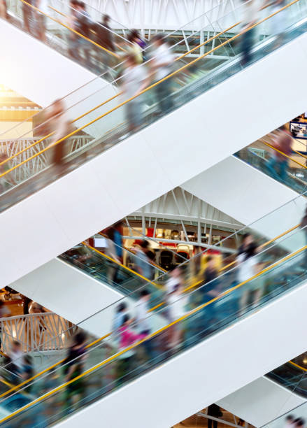 People on many fast moving escalators in modern shopping mall stock photo
