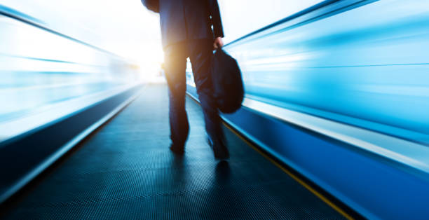 uomini d'affari che camminano alla scala mobile mobile nell'aeroporto - moving walkway escalator airport walking foto e immagini stock