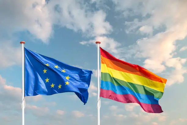 Waving European Union and rainbow flag in front of a moody sky