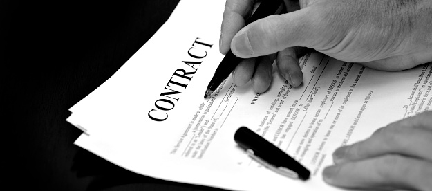Contract on desk with black pen being signed by business person