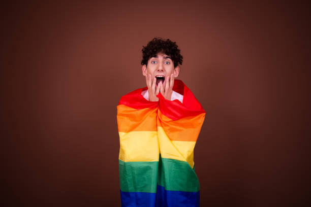 istock Attractive guy posing with a gay flag on a brown background. 1583093555
