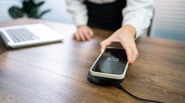 istock Charging mobile phone battery with wireless charging device in the table. Smartphone charging on a charging pad. Mobile phone near wireless charger Modern lifestyle technology concept. 1583094797