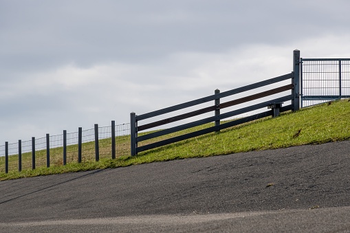 A wooden fence with a white bench positioned nearby in a scenic outdoor setting atop a grassy hill