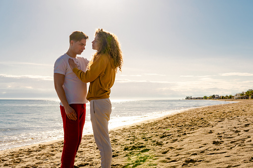 Loving young couple on coastline at summer sunset after arguing