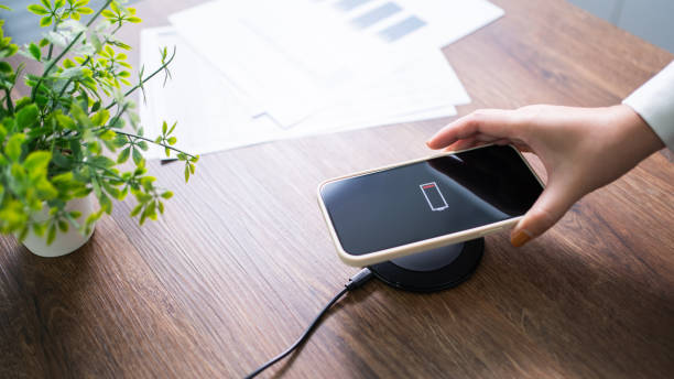 istock Charging mobile phone battery with wireless charging device in the table. Smartphone charging on a charging pad. Mobile phone near wireless charger Modern lifestyle technology concept. 1583116879