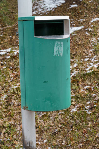 istock Green trash can on metallic pole with grass and snow background 1583136859