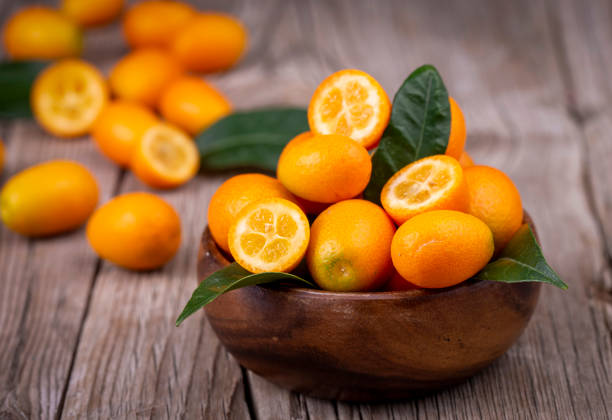 vista superior de un montón de kumquats frescos en el mercado de alimentos orgánicos. - kumquat fotografías e imágenes de stock