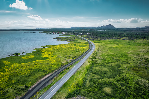 Aerial view of highway road through mossy remote wilderness by coastline in summer at Iceland