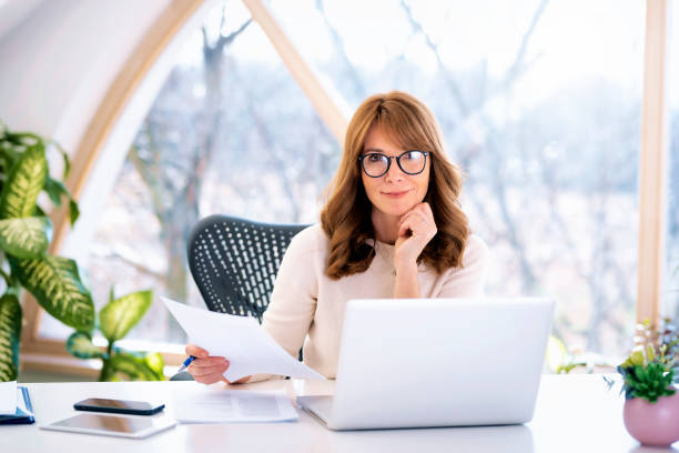 istock Mid aged businesswoman sitting at desk and using laptop for work 1583168629