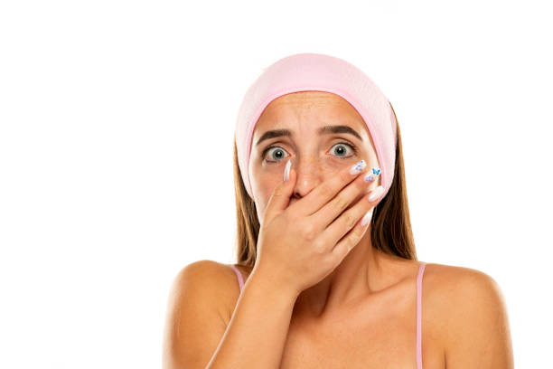 Shocked young woman covers her mouth with her hand on a white background