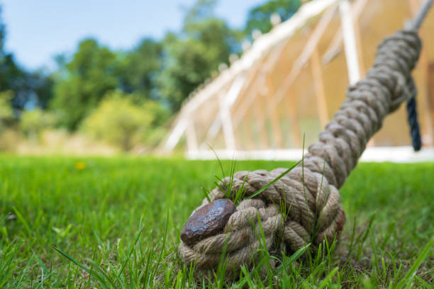 Shallow focus of a large metal marquee peg and rope seen anchored into soft grass.