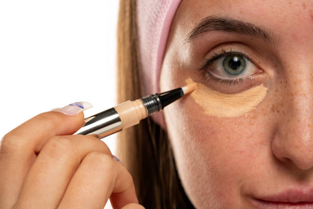 istock Young woman applyes concealer under her eyes 1583171091