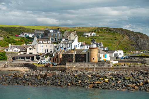 Portpatrick, Scotland, UK - 5th July 2023: Part of the village of Portpatrick, Dumfries and Galloway, featuring the lighthouseand shore defences. There has been a lighthouse here since 1744.